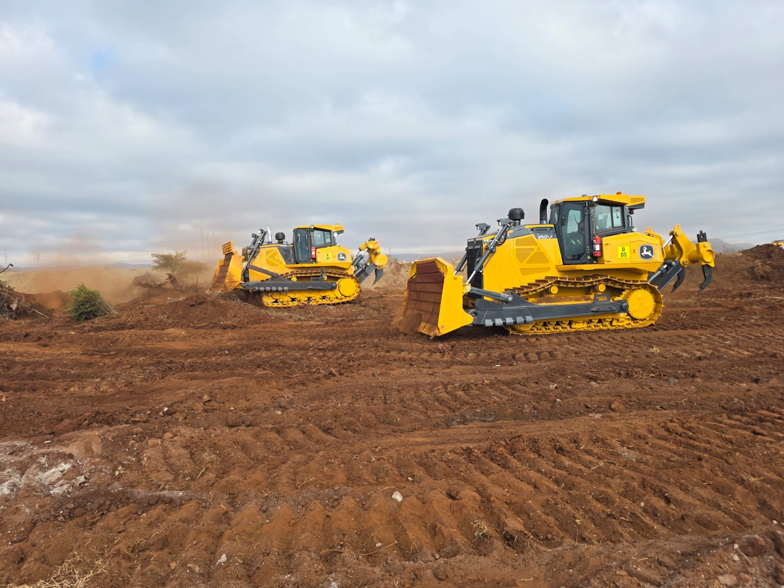 Two yellow tracked earthmoving machines working on a cleared site